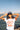 Person wearing a white t-shirt with red graphics and text, standing by a waterfront with a city skyline in the background.