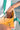 A person holding a cream-colored bag with green straps, in a close-up of their hand and the bag.