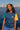 Woman standing by a waterfront with a city skyline in the background