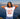 Woman wearing a white t-shirt with red accents and a graphic design, standing by a waterfront with a city skyline in the background.