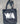 Black tote bag with 'WA' printed on it, lying on a textured surface.