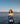 Woman with a 'WA' bag standing by the water with ships in the background