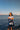 Woman with a 'WA' bag standing by the water with ships in the background